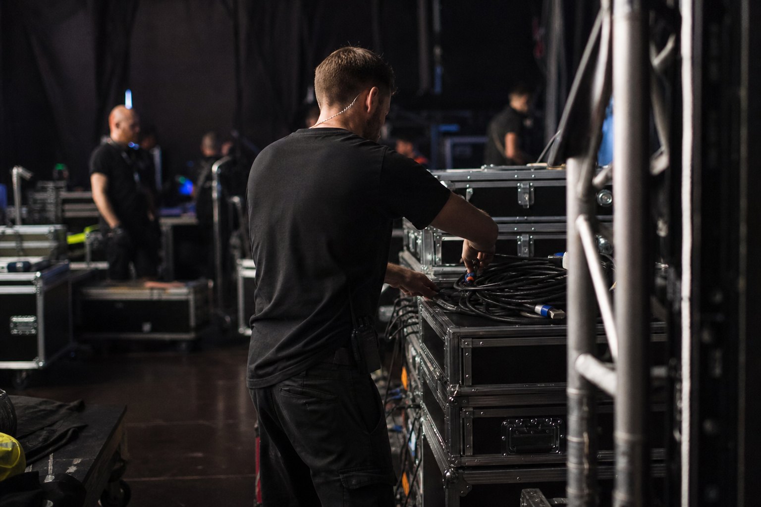 Technika sceniczna Będzin - backstage eventu z case'ami, kablami i ekipą w czerni podczas montażu